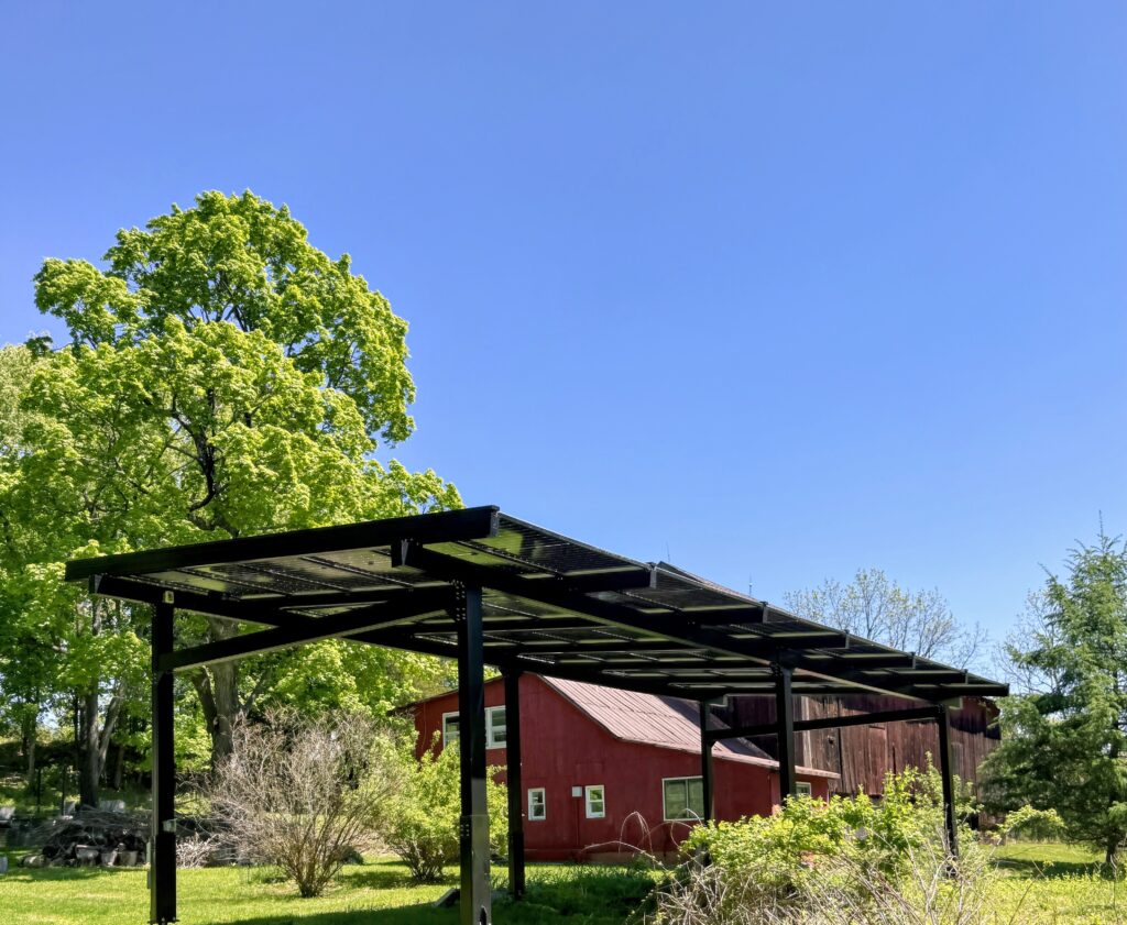 Solar pergola overlooking a landscaped rural property beside a barn